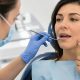 Dentista revisando la boca de una paciente que señala una molestia